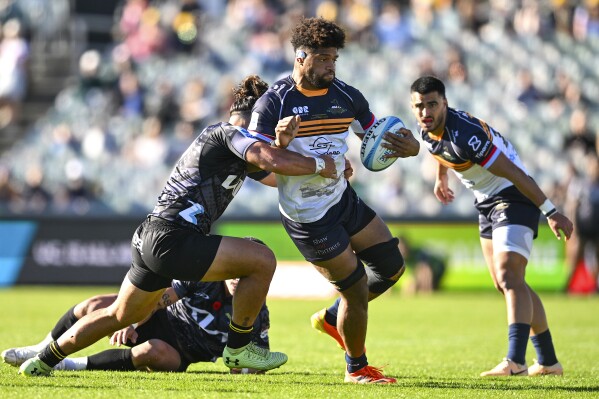 Rob Valetini of the Brumbies is tackled by Peter Umaga-Jensen of the Hurricanes during the Super Rugby in Canberra, Australia, Saturday, April 27, 2024. (Lukas Coch/AAP Image via AP)