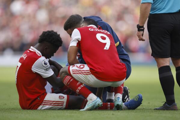 Arsenal's Bukayo Saka, left sits injured on the pitch speaking to teammate Arsenal's Gabriel Jesus during the English Premier League soccer match between, Arsenal and Nottingham Forrest at the Emirates stadium in London, Sunday, Oct. 30, 2022. (AP Photo/David Cliff)