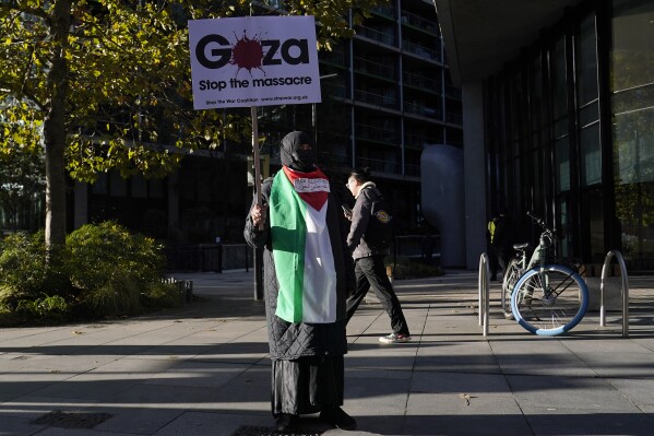 A protester shows a placard during a pro-Palestinian protest in London, Saturday, Nov. 11, 2023. London police have stepped up efforts to ensure a pro-Palestinian march on Saturday remains peaceful following a week of political sparring over whether the demonstration should go ahead on the weekend Britain honors its war dead.(AP Photo/Alberto Pezzali)