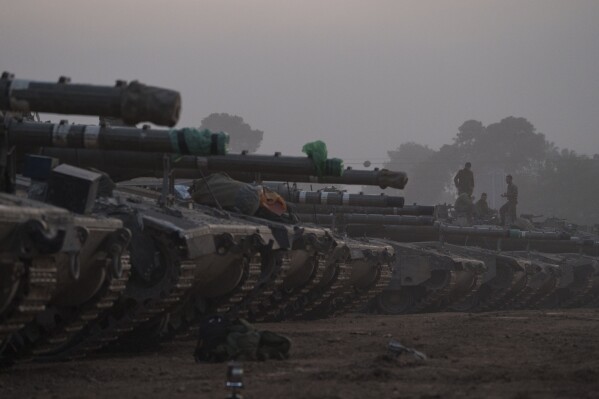 Israeli soldiers stand on top of a tank in a staging area at the Israeli-Gaza border in southern Israel, Monday, Jan. 1, 2024. The army is battling Palestinian militants across Gaza in the war ignited by Hamas' Oct. 7 attack into Israel. (AP Photo/Leo Correa)
