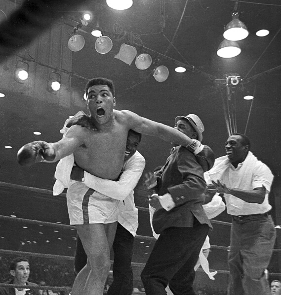 Cassius Clay's handlers hold him back as he reacts after he is announced the new heavyweight champion of the world on a seventh round technical knockout against Sonny Liston at Convention Hall in Miami Beach, Fla., on Feb. 25, 1964.  (AP Photo)