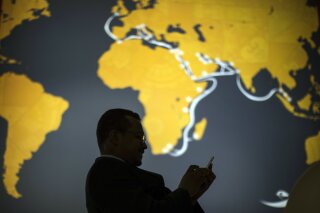FILE - In this Feb. 26, 2018, file photo a visitor uses his phone during the Mobile World Congress wireless show, in Barcelona, Spain. Facebook’s new Libra digital currency is aimed at a huge potential market for financial services, the entire developing world, with billions of people in areas such as India and Sub-Saharan Africa, where financial services are often less sophisticated and many people don’t use traditional banking accounts. (AP Photo/Emilio Morenatti, File)