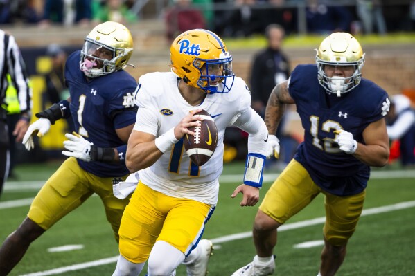 Pittsburgh quarterback Christian Veilleux (11) runs away from Notre Dame defensive lineman Javontae Jean-Baptiste (1) and defensive lineman Jordan Botelho (12) during the second half of an NCAA college football game Saturday, Oct. 28, 2023, in South Bend, Ind. (AP Photo/Michael Caterina)