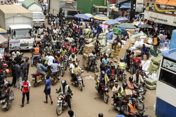 Drivers of motorcycle taxis, known locally as boda-bodas, ride with passengers on a street of Kampala, Uganda, on July 18, 2024. (AP Photo/Hajarah Nalwadda )