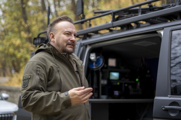 Serhii Beskrestnov, more widely known as Flash, a Ukrainian electronics expert who hunts drones for the military, stands near his kitted-out black van in Kyiv, Ukraine, Nov. 4, 2024. (AP Photo/Hanna Arhirova, File)