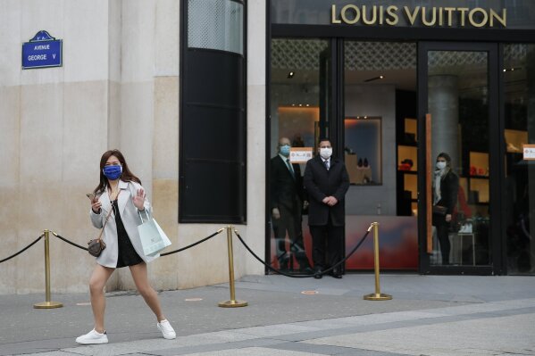 A man wearing a protective masks walks out of a Chanel store on its  reopening on the Champs Elysee avenue in Paris, France on May 11, 2020.  France began a gradual easing