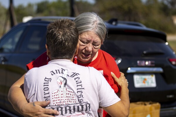 Yolanda Fraser, Kaysera Stops Pretty Places' grandmother, gets a hug before a dedication ceremony for a billboard in support of the Missing and Murdered Indigenous People movement on Tuesday, Aug. 29, 2023, along I-90 in Hardin, Mont. (AP Photo/Mike Clark)