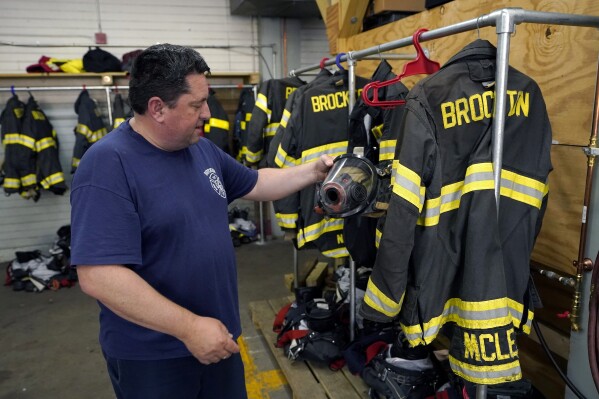 Firefighter William Hill, of Brockton, Mass., displays protective gear at Station 1, Thursday, Aug. 3, 2023, in Brockton, Mass. Firefighters around the country are concerned that gear laced with the toxic industrial compound PFAS could be one reason why cancer rates among their ranks are rising. The chemical, which has been linked to health problems including several types of cancer, is used in turnout gear to repel water and other substances when fighting a fire. (AP Photo/Steven Senne)
