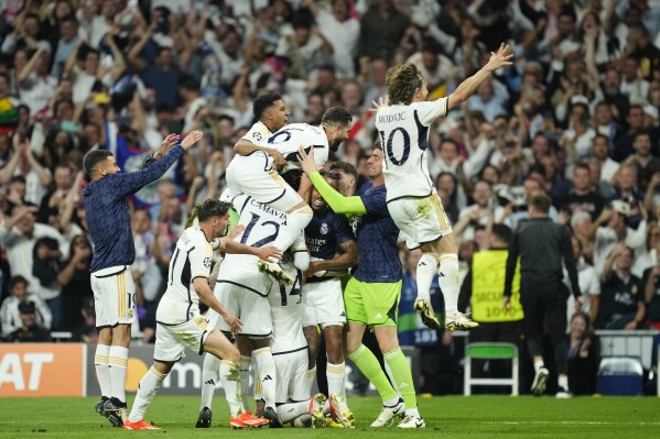 Real Madrid's Joselu, covered by his teammates, celebrates after scoring his side's second goal during the Champions League semifinal second leg soccer match between Real Madrid and Bayern Munich at the Santiago Bernabeu stadium in Madrid, Spain, Wednesday, May 8, 2024. (AP Photo/Jose Breton)