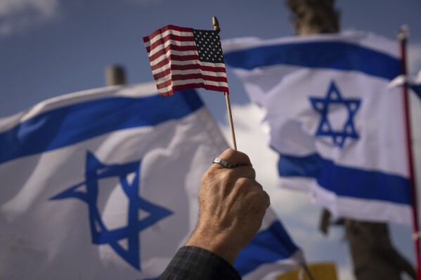 FILE - Israelis opposed to a contentious government plan to overhaul the judiciary wave Israeli and American flags during a protest in support of President Joe Biden, who criticized the plan this week, outside of the U.S. Embassy Branch Office in Tel Aviv, Israel, March 30, 2023. As Biden prepares to meet Israeli Prime Minister Benjamin Netanyahu this week in New York, a new poll finds that while Americans generally view Israel as a partner or ally, many question whether his far-right government shares American values. (AP Photo/Oded Balilty, File)