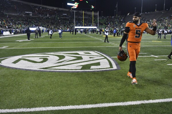 Oregon State quarterback DJ Uiagalelei (5) walks by the Pac-12 logo and waves to fans after the team's NCAA college football game against Oregon, Friday, Nov. 24, 2023, in Eugene, Ore. This was the final Pac-12 football game for the team. (AP Photo/Mark Ylen)