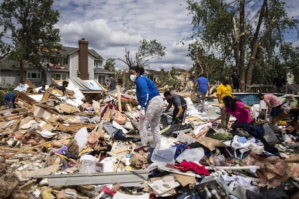 Dozens of volunteers help clean up a demolished home on Princeton Circle near Ranchview Drive in Naperville after a tornado ripped through the western suburbs overnight, Monday afternoon, June 21, 2021. (Ashlee Rezin Garcia/Sun-Times/Chicago Sun-Times via AP)