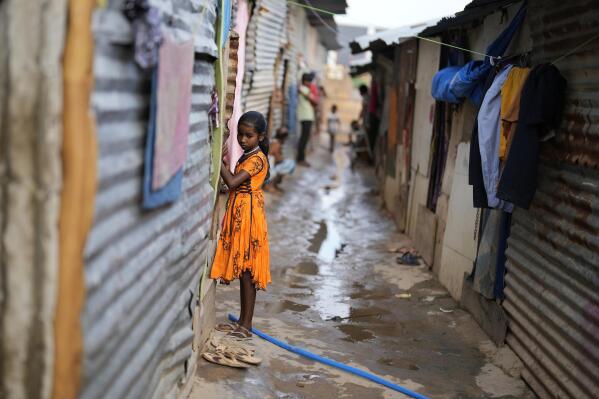 Jerifa Islam stands outside her home in a poor neighborhood in Bengaluru, India, Wednesday, July 20, 2022. A flood in 2019 in the Darrang district of India's Assam state started Jerifa Islam, her brother Raju and their parents on a journey that led the family from their Himalayan village to the poor neighborhood. (AP Photo/Aijaz Rahi)