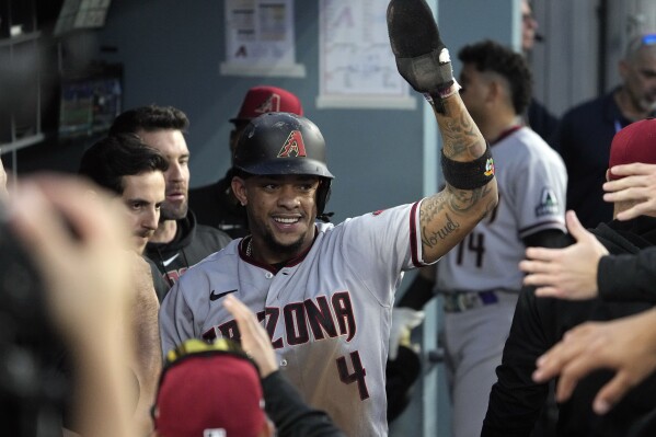 Arizona Diamondbacks' Ketel Marte celebrates in the dugout after scoring on an RBI single by Corbin Carroll during the first inning in Game 1 of a baseball NL Division Series against the Los Angeles Dodgers, Saturday, Oct. 7, 2023, in Los Angeles. (AP Photo/Mark J. Terrill)