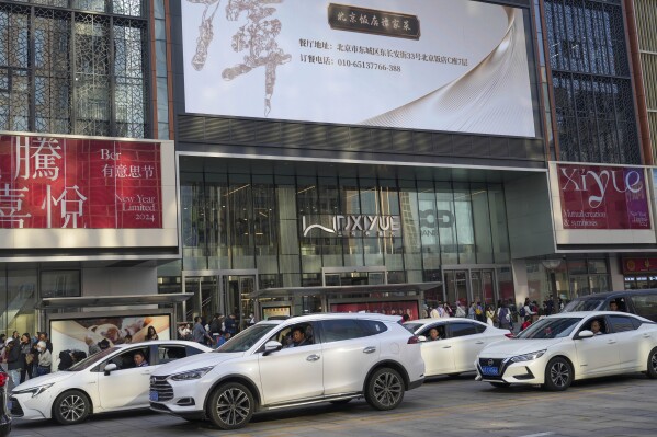 People look out from their car windows during rush hour traffic near a shopping mall in Beijing, China, Friday, April 5, 2024. (AP Photo/Tatan Syuflana)