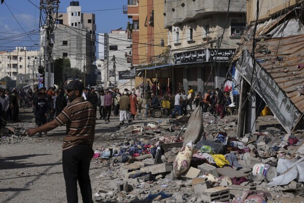 Palestinians gather in front of a building hit by an Israeli on the Gaza Strip in Nusseirat refugee camp, central Gaza Strip, Tuesday, Nov. 21, 2023. (AP Photo/Adel Hana)