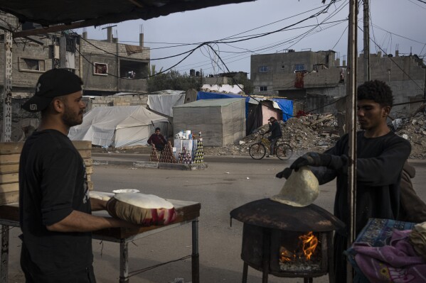 Palestinians bake bread on a street in Rafah, Gaza Strip, Friday, Feb. 23, 2024. An estimated 1.5 million Palestinians displaced by the war took refuge in Rafahor, which is likely Israel's next focus in its war against Hamas.(AP Photo/Fatima Shbair)