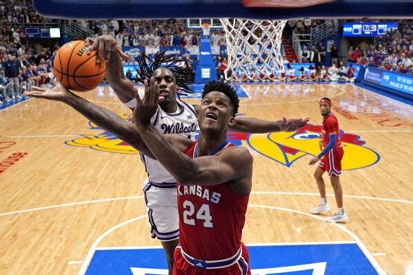 Kansas State forward Arthur Kaluma, back, blocks a shot by Kansas forward K.J. Adams Jr. (24) during the first half of an NCAA college basketball game against Kansas State Tuesday, March 5, 2024, in Lawrence, Kan. (AP Photo/Charlie Riedel)