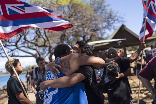 Lahaina, Hawaii, residents, who are affected by a deadly wildfire that devastated the community, hug one another after a news conference in Lahaina, Hawaii, Friday, Aug. 18, 2023. (AP Photo/Jae C. Hong)