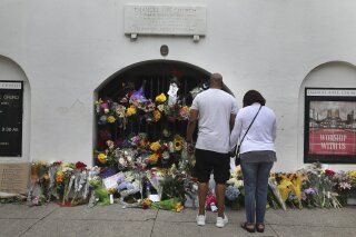 Visitors, including Matt and Marsha Bacoate, leave flowers, notes ad prayers at Emanuel AME Church on the five-year anniversary of the shooting Wednesday, June 17, 2020, in Charleston, S.C. Dylann Roof, shot a killed nine people while they were in a bible study at the church. (Grace Beahm Alford/The Post And Courier via AP)