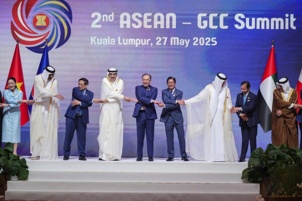 Thailand's Prime Minister Paetongtarn Shinawatra, Emir of Qatar Sheikh Tamim bin Hamad Al Thani, Vietnam's Prime Minister Pham Minh Chinh, Kuwait's Crown Prince Sheikh Sabah Khalid Al Sabah, Malaysia's Prime Minister Anwar Ibrahim, Philippines' President Ferdinand Marcos Jr., Ruler of the UAE's Emirate of Ras al-Khaimah Sheikh Saud bin Saqr al Qasimi, Burunei's Sultan Hassanal Bolkiah, Bahrain's Crown Prince Salman bin Hamad al-Khalifa, chain their hands as they pose for a group photo at the 2nd ASEAN-Gulf Cooperation Council (GCC) Summit after the 46th Association of Southeast Asian Nations (ASEAN) Summit in Kuala Lumpur, Malaysia, Tuesday, May 27, 2025. (AP Photo/Vincent Thian)