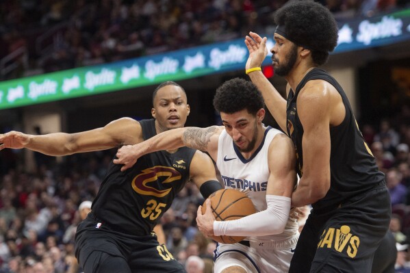 Memphis Grizzlies' Scotty Pipen Jr., center, is defended by Cleveland Cavaliers' Jarrett Allen, right, and Isaac Okoro (35) during the second half of an NBA basketball game in Cleveland, Wednesday, April 10, 2024. (AP Photo/Phil Long)