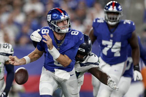New York Giants quarterback Daniel Jones (8) fumbles the ball as he is hit by Seattle Seahawks defensive end Mario Edwards Jr. (97) during the second quarter of an NFL football game, Monday, Oct. 2, 2023, in East Rutherford, N.J. (AP Photo/Adam Hunger)