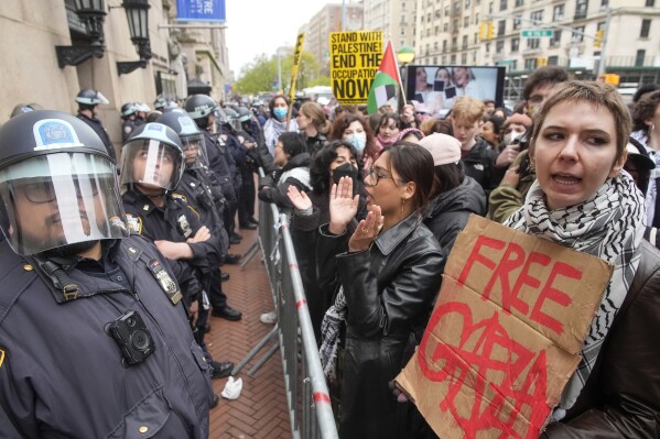 Police in Riot gear stand guard as demonstrators chant slogans outside the Columbia University campus, Thursday, April 18, 2024, in New York. The protesters were calling for the school to divest from corporations they claim profit from the war in the Middle East. (AP Photo/Mary Altaffer)