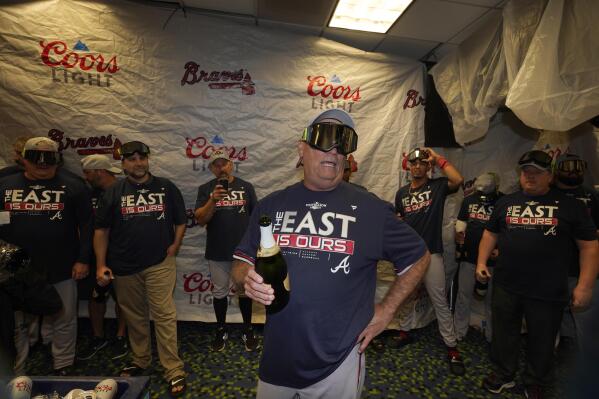 Atlanta Braves manager Brian Snitker, center, talks to players as they celebrate in the club house after clinching their fifth consecutive NL East title by defeating the Miami Marlins 2-1, in a baseball game, Tuesday, Oct. 4, 2022, in Miami. (AP Photo/Wilfredo Lee)