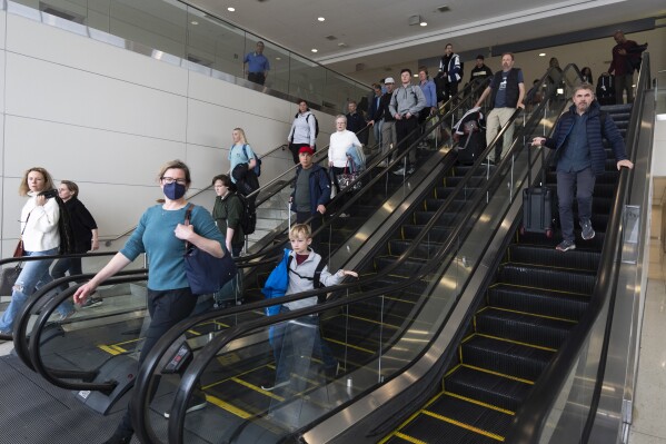 International travelers go down the escalator to get processed at the port of entry at Washington Dulles International Airport in Chantilly, Va. Monday, April 1, 2024. (AP Photo/Manuel Balce Ceneta)