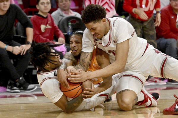 Arkansas players Khalif Battle, left, and Jalen Graham, right, and Tennessee guard Zakai Zeigler scramble for control of the ball during the first half of an NCAA college basketball game Wednesday, Feb. 14, 2024, in Fayetteville, Ark. (AP Photo/Michael Woods)