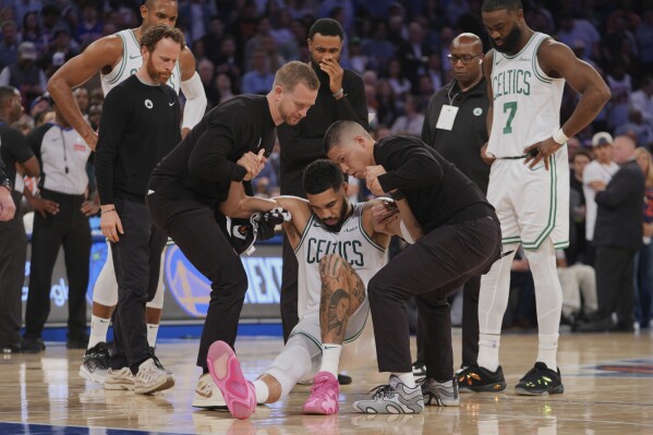 Trainers help Boston Celtics' Jayson Tatum (0) off the court after he was injured during the second half of Game 4 in the Eastern Conference semifinals of the NBA basketball playoffs against the New York Knicks Monday, May 12, 2025, in New York. (AP Photo/Frank Franklin II)