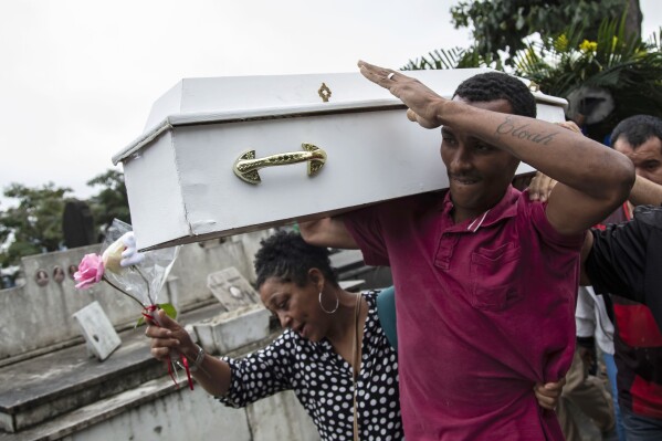 Gilgres Santos, the father of five-year-old Eloah Passos, carries his daughter's remains for a burial at Cacuia Cemetery two days after she was killed by a stray bullet in Rio de Janeiro, Brazil, Monday, Aug. 14, 2023. Passos died on Saturday, Aug. 12, while at home in the Dende favela. (AP Photo/Bruna Prado)