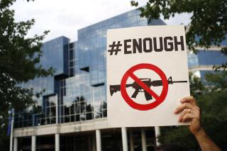 FILE - A protester holds a sign outside the National Rifle Association's headquarters building during a vigil for recent victims of gun violence on Aug. 5, 2019, in Fairfax, Va. A ransomware gang believed to operate out of Russia says it hacked the National Rifle Association, a politically powerful gun-rights group. The gang, which calls itself Grief, published a handful of what appear to be NRA files related to grants the organization has awarded. (AP Photo/Patrick Semansky, File)