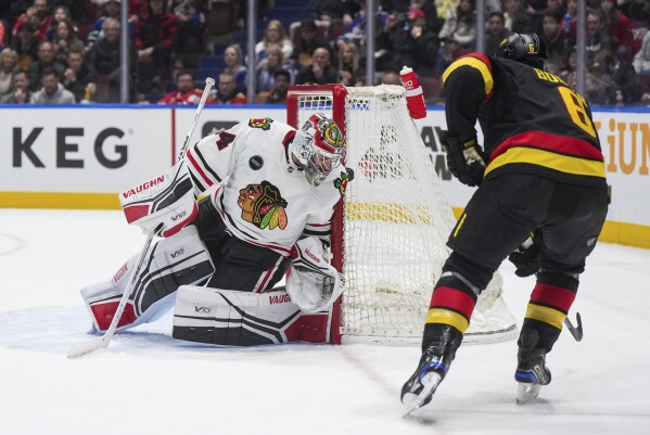 Chicago Blackhawks goalie Petr Mrazek, left, stops Vancouver Canucks' Brock Boeser during the second period of an NHL hockey game in Vancouver, British Columbia, Monday, Jan. 22, 2024. (Darryl Dyck/The Canadian Press via AP)