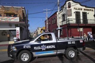 FILE - In this Feb. 10, 2020 file photo, a policeman drives past town hall in Apaseo El Alto, Guanajuato state, Mexico. The notoriously violent Jalisco cartel has responded to Mexico's “hugs, not bullets” policy with a policy of their own: the cartel kidnapped in mid-May 2021, several members of an elite police force in the state of Guanajuato, tortured them to obtain names and addresses of fellow officers, and are now hunting down and killing police at their homes, on their days off, in front of their families. (AP Photo/Rebecca Blackwell, File)