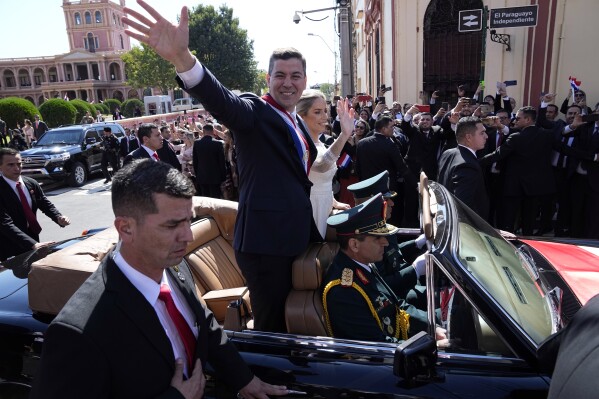 Paraguay's newly sworn-in President Santiago Pena and wife Leticia Ocampos wave from a car taking them to the Cathedral on Pena's inauguration day in Asuncion, Paraguay, Tuesday, Aug. 15, 2023. (AP Photo/Jorge Saenz)