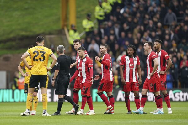 Match referee Darren Bond speaks with the Sheffield United players following an altercation between Sheffield United's Jack Robinson, second right and teammate Anel Ahmedhodzic, fourth left, during the English Premier League soccer match between Wolverhampton Wanderers and Sheffield United, at Molineux Stadium, in Wolverhampton, England, Sunday, Feb. 25, 2024. (Mike Egerton/PA via AP)