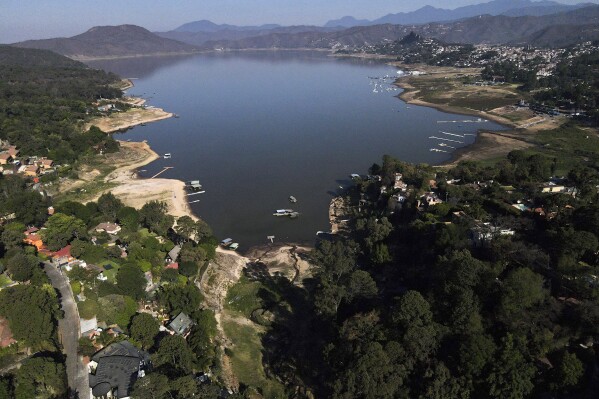 The banks of the Miguel Aleman dam lie exposed due to low water levels in Valle de Bravo, Mexico, Thursday, March 14, 2024. According to Mexico’s National Water Commission, Valle de Bravo’s reservoir has fallen to 29% of its capacity – a historical low -- compared to one year ago when it was at 52%, while the country endures a drought and has imposed restrictions on water taken from the system. (AP Photo/Marco Ugarte)