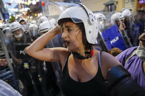 A protester, wearing a helmet of a riot police officer walks away during clashes with police officers preventing the group from marching against the government's decision to withdraw from Istanbul Convention, in Istanbul, Thursday, July 1, 2021. Turkey formally withdrew Thursday from a landmark international treaty protecting women from violence, and signed in its own city of Istanbul, though President Recep Tayyip Erdogan insisted it won’t be a step backwards for women. Hundreds of women demonstrated in Istanbul later Thursday, holding banners that said they won't give up on the Council of Europe’s Istanbul Convention. (AP Photo/Kemal Aslan)