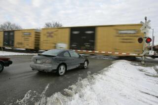 FILE - Cars wait for a train to pass, in Valley, Neb., Wednesday, Jan. 17, 2007. With the rail industry relying on longer and longer trains to cut costs, the Biden administration is handing out $570 million in grants to help eliminate railroad crossings in 32 states. The grants announced Monday, June 5, 2023 will help eliminate more than three dozen crossings that delay traffic and sometimes keep first responders from where help is desperately needed. (AP Photo/Nati Harnik, File)
