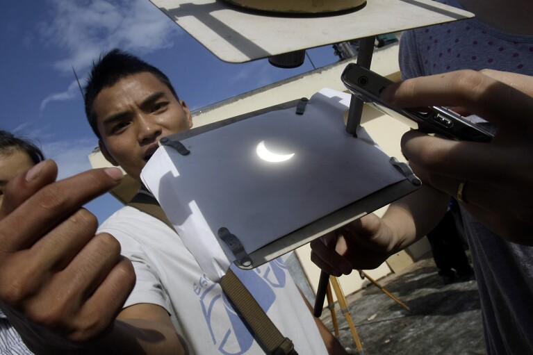 FILE - Vietnamese student Dang Anh Tuan shows a projected image of a solar eclipse at an observatory in Hanoi National University of Education in Hanoi, Vietnam, Wednesday, July 22, 2009, during the longest total solar eclipse of the 21st century, though in most of Vietnam, people will only be able to see a partial eclipse. (AP Photo/Chitose Suzuki, File)