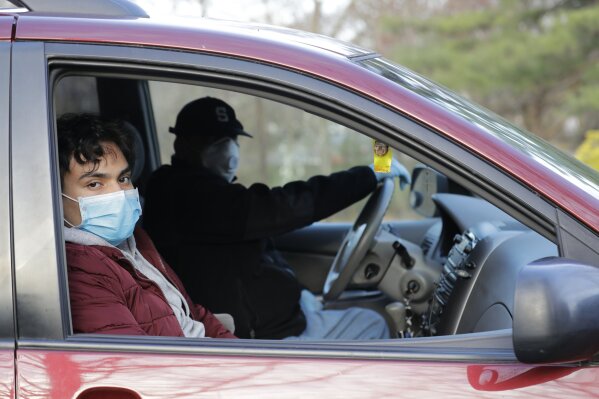 In this April 7, 2020, photo, Alexander Carpio poses for a picture in his car while waiting in line to be tested for the new coronavirus, in Paramus, N.J. (AP Photo/Seth Wenig)