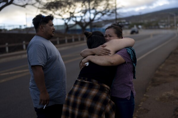 Nora Bulosan, right, and Hannah Tomas, Lahaina, Hawaii residents who survived the fire that devastated the town, comfort each other as they gather in hopes to get access to their home in Lahaina, Hawaii, Wednesday, Aug. 16, 2023. (AP Photo/Jae C. Hong)