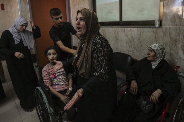 En el hospital de al-Aqsa en Deir el-Balah, en el centro de la Franja de Gaza, una mujer palestina reacciona junto a los heridos durante un ataque aéreo israelí, el domingo 15 de octubre de 2023. (Foto AP/Adel Hana)