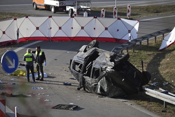 Police attendants stand by an overturned vehicle on highway A94 near Muehldorf, Germany, Friday, Oct. 13, 2023. A vehicle trying to evade a police check in southern Germany left a highway at high speed on Friday and crashed, killing seven people, authorities said. The overcrowded vehicle appeared to be carrying migrants. The accident happened near Muehldorf, east of Munich on the A94 highway, which leads to the Austrian border. (Sven Hoppe/dpa via AP)