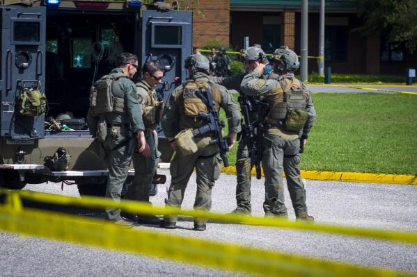 Members of the Virginia State Police SWAT Team gather behind a Bearcat tactical vehicle after clearing Heritage High School in Newport News, Va., Monday, Sept. 20, 2021, following a shooting at the school. (AP Photo/John C. Clark)