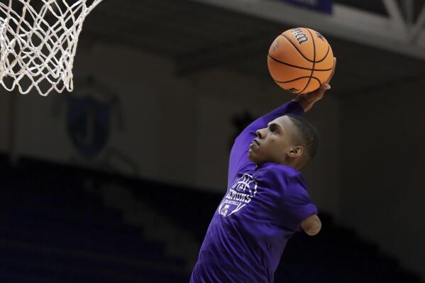 Hansel Enmanuel, a freshman guard from the Dominican Republic for Northwestern State, practices dunks during warm-ups before an NCAA college basketball game against Rice Saturday, Dec. 17, 2022, in Houston. Enmanuel lost his left arm in a childhood accident and has attained the talent and skill to play at the college level. (AP Photo/Michael Wyke)