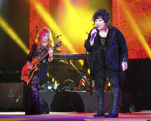 FILE - Nancy Wilson, left, and Ann Wilson of Heart perform on opening night of the Heartbreaker Tour at the Cruzan Amphitheater in West Palm Beach, Fla., June 17, 2013. Heart — the pioneering band that melds Nancy Wilson’s shredding guitar with her sister Ann’s powerhouse vocals — is hitting the road this spring for a world tour that Nancy Wilson describes as “the full-on rocker size.” (Photo by Jeff Daly/Invision/AP, File)