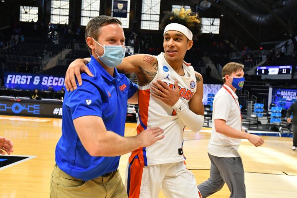 Florida head coach Mike White embraces Tre Mann after they defeated Virginia Tech in a college basketball 
game in the first round of the NCAA tournament at Hinkle Fieldhouse in Indianapolis, Ind., Friday, March 19, 2021.  Florida defeated Virginia 75-70. (Brett Wilhelm/Pool Photo via AP)